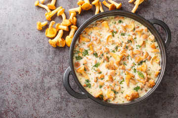 Chanterelle mushrooms are stewed in cream wine sauce closeup in a pan on a table. Horizontal top view from above