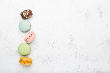 macaroons in different colors on a white cement background. Top view, space for text