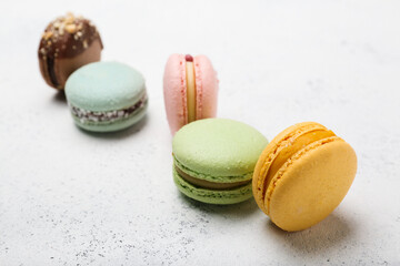 macaroons in different colors on a white cement background. 