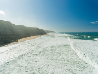 Cliffs of Atlantic Ocean in Portugal. Waves are crashing on the empty beach.