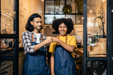 Young  couple asian man and african woman manager in restaurant with digital tablet or notebookWoman coffee shop owner with face mask hold open sign .Small business concept.