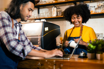 Young couple  manager in restaurant with digital tablet or notebook.Close up of joyful African American young woman worker in apron stands in cafe restaurant.Small business concept.