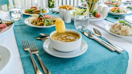 Table setting for a dinner, lentil soup with lemon and salad is ready to eat