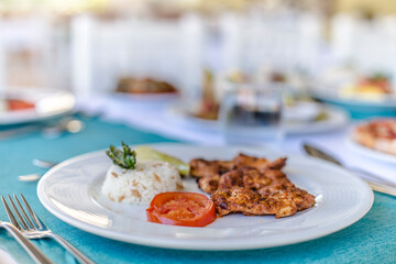Served table in restaurant. Grilled chicken, rice and salad table.