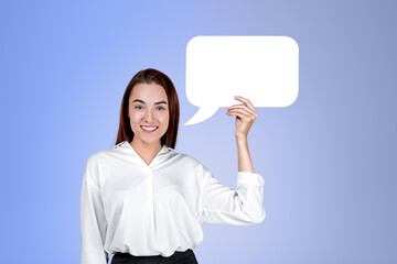 Young businesswoman holding a mockup speech bubble on blue background