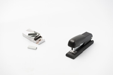 The black office stapler with paper clips container on the white background