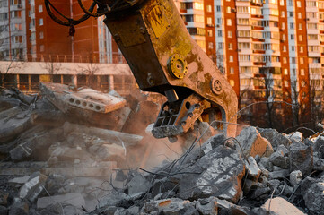 Concrete crusher works with pile of cement stones closeup