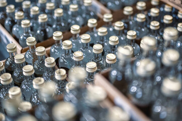 Glass bottles of vodka closed with golden caps in workshop - obrazy, fototapety, plakaty