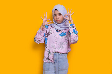 young asian beautiful muslim woman with ok sign gesture tumb up isolated on yellow background
