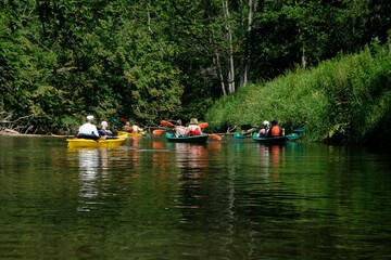 People in kayaks on water during kayaking in nature reserve "Refuge of beavers on the Pasleka river" in Warmia and Mazury, Poland