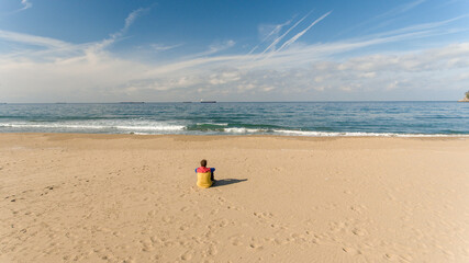 Lonely man sitting on the calm beach, thinking and self observing