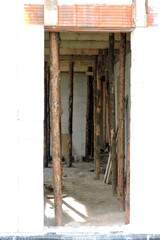 A rough door opening, reinforced brick lintels, walls made of autoclaved aerated concrete and wooden building props inside a house under construction

