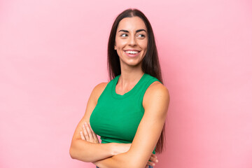 Young caucasian woman isolated on pink background with arms crossed and happy