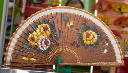 Un hermoso y tradicional abanico español con diseño floral para darse aire durante los calurosos días de verano - obrazy, fototapety, plakaty