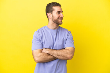 Handsome blonde man over isolated yellow background happy and smiling