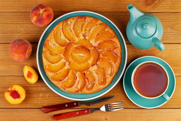 Homemade pie with peaches and cup of tea on wooden table. Top view.