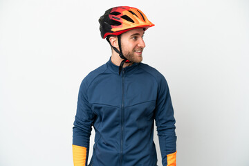 Young cyclist man isolated on white background looking to the side and smiling
