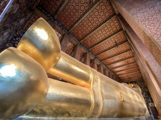 Wat Pho Temple in Bangkok, Thailand with huge lying golden Buddha statue, colorful ceiling and wall...