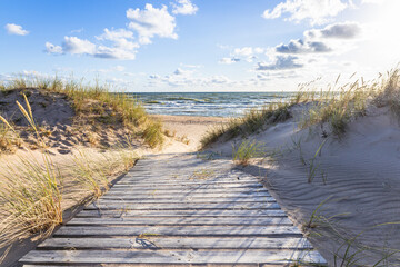The path through dunes to the sandy beach on the Baltic Sea in summer with a blue sky