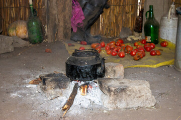The interior of a reed house in Africa, with a traditional tea kettle over a firewood and stones...