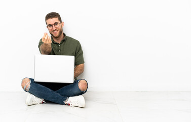 Young man sitting on the floor making money gesture