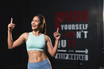 Smiling Asian athlete woman in sportswear slim muscular body posing action after exercise in...