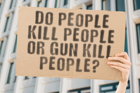The question " Do people kill people or gun kill people? " is on a banner in men's hands with blurred background. Safety. Shot. Target. Shooting. Assassin. Combat. Terrorist. Armed. Robber. Guard