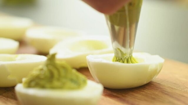 Preparing deviled eggs with avocado and basil.
