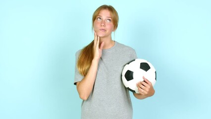 Young pretty blonde woman thinking and holding a soccer ball over isolated background - Powered by Adobe