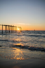 Fototapeta premium Ruins of an old bridge on a beautiful beach with sun flare