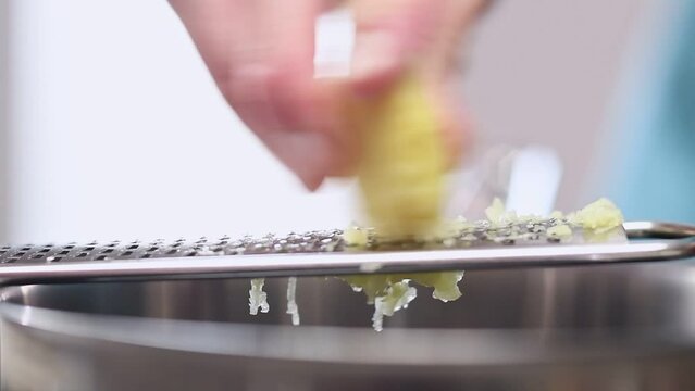 Grating ginger root with a grater in the kitchen.
