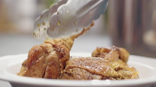 Chef serves freshly prepared braised chicken with garlic and oregano.
