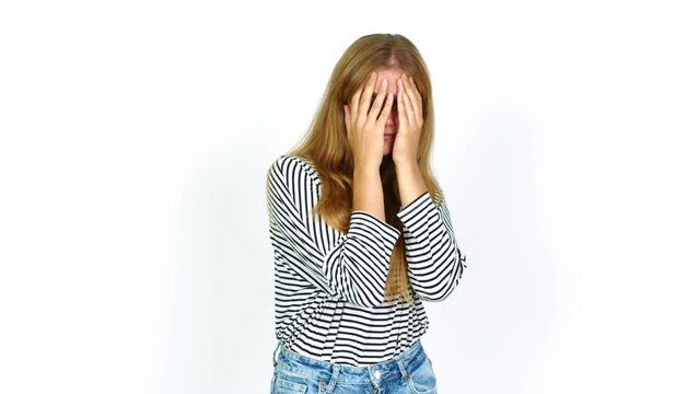 Young pretty blonde woman covering eyes by hands and looking through the fingers over isolated background