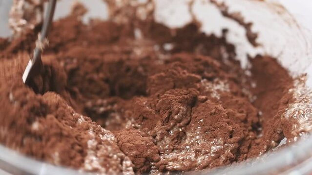Process of making chia pudding with cocoa. Stirring ingredients in a glass bowl.
