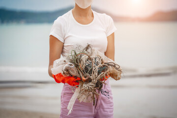 A female ecologist volunteer cleans the beach on the seashore from plastic and other waste