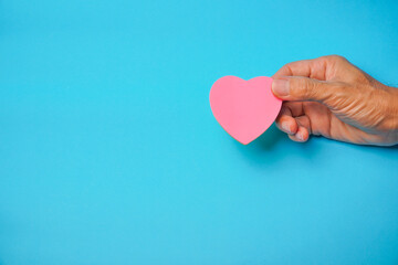 Red ribbon in hand with blue background, heart health, donate, happy volunteer charity, corporate...