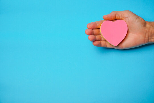 Red ribbon in hand with blue background, heart health, donate, happy volunteer charity, corporate social responsibility, world heart day, world health day, world mental health day,  concept