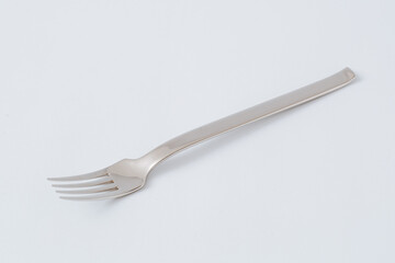 Stainless steel fork for eating on white background, kitchenware, copy space, close-up