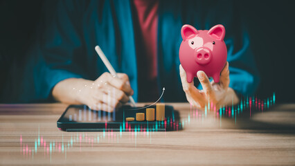 Closeup image of a pink piggy bank and taking note on the tablet for planning, saving money wealth...