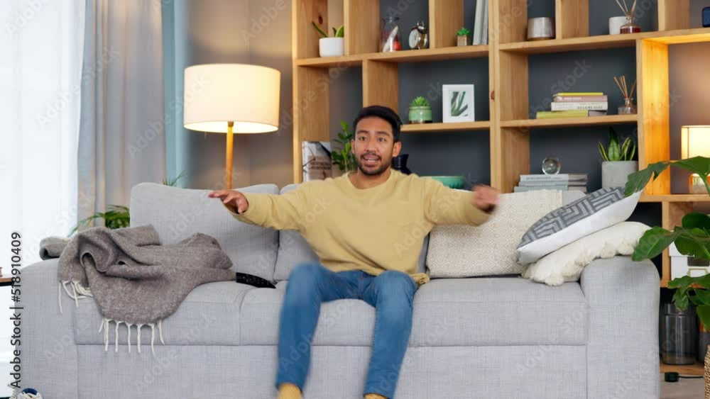 Canvas Prints Carefree young man jumping over and onto the sofa to sit and relax at home. Happy guy smiling and laughing while watching funny videos, series or movies on the TV in his living room over the weekend