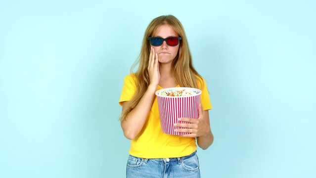 Young pretty blonde woman eating popcorns in a big bowl over isolated background