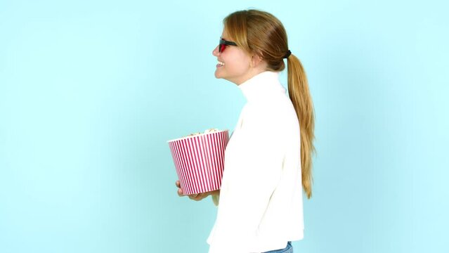 Young pretty blonde woman holding a bowl of popcorns over isolated background