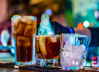 hands of a bartender with black gloves making cocktail on a bar counter.