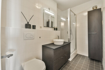 Shower faucets attached to tiled wall near glass partition and ornamental curtail in washroom at...