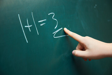 A teenager's hand shows an incorrectly solved example on a green blackboard. The concept of education and training.
