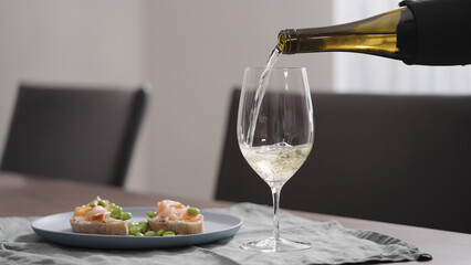 pour white wine into glass on walnut table