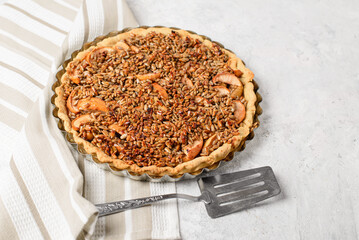 Homemade sunflower seed cake in a baking dish with a spatula on a striped napkin