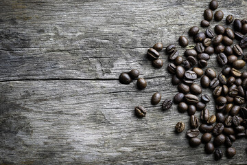 picture of coffee beans stacked on wooden floor on a dark background with copy space