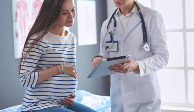 Beautiful smiling pregnant woman with the doctor at hospital