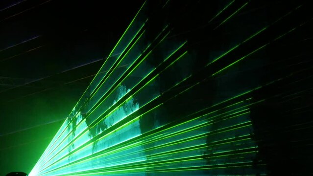Light laser show on a black background of the night sky, outdoor performance. Multi-colored laser beams turn into various shapes, projection on smoke. Information Technology Conference